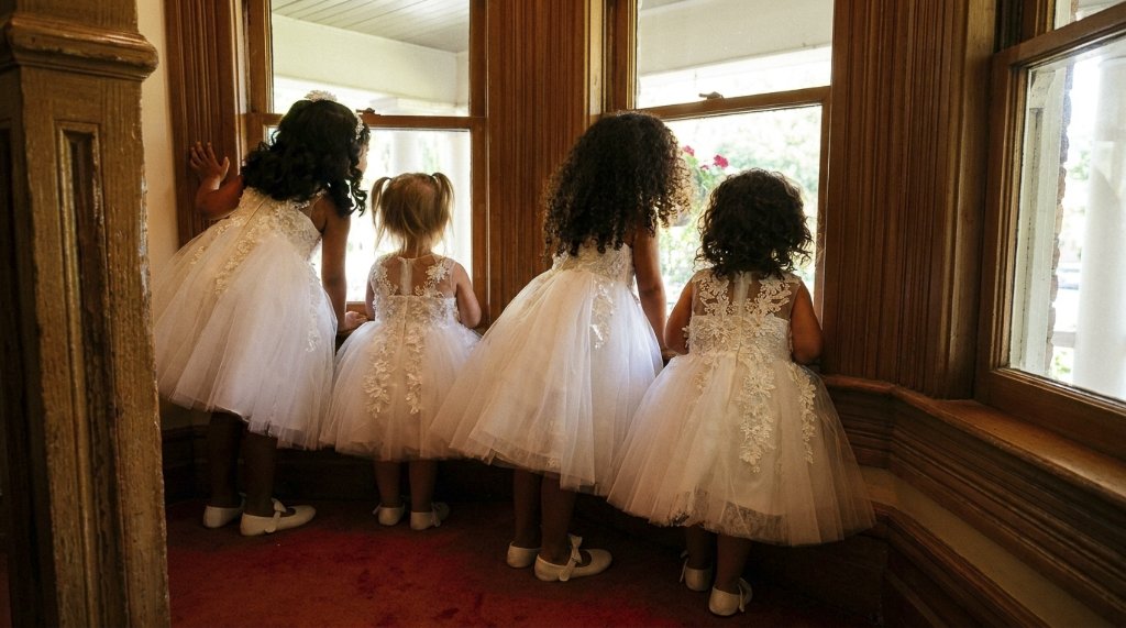 Flower girls looking out a window before the ceremony