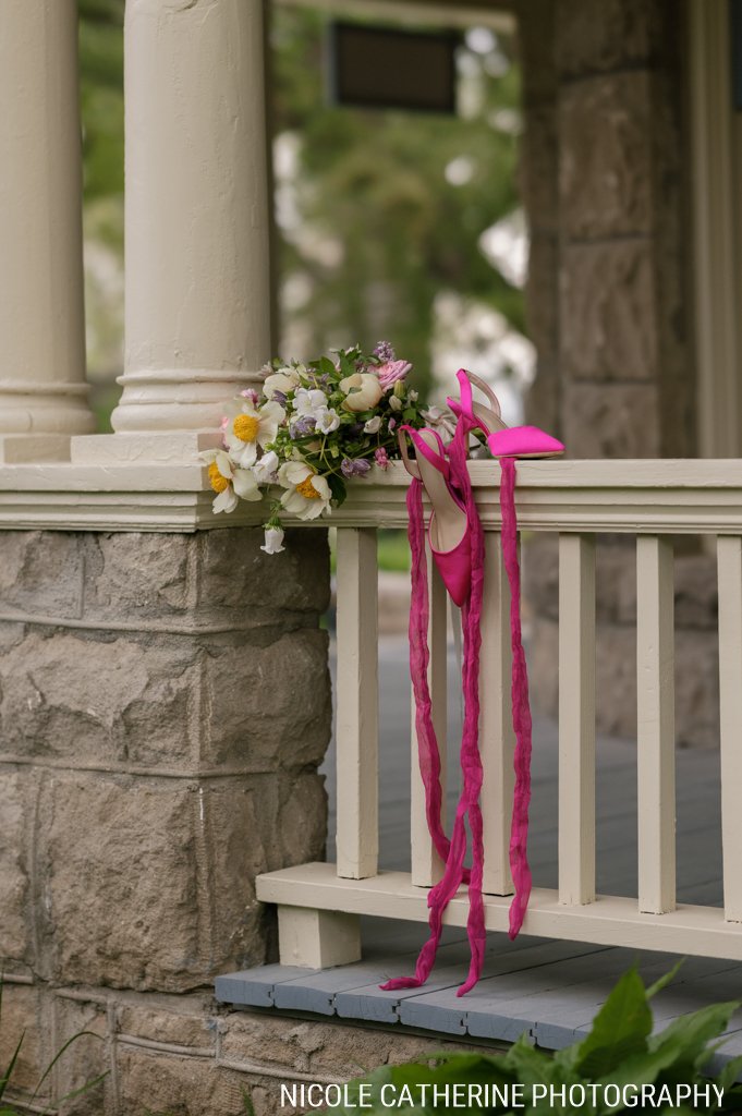 Bridal bouquet and pink ribboned heels on the porch railing