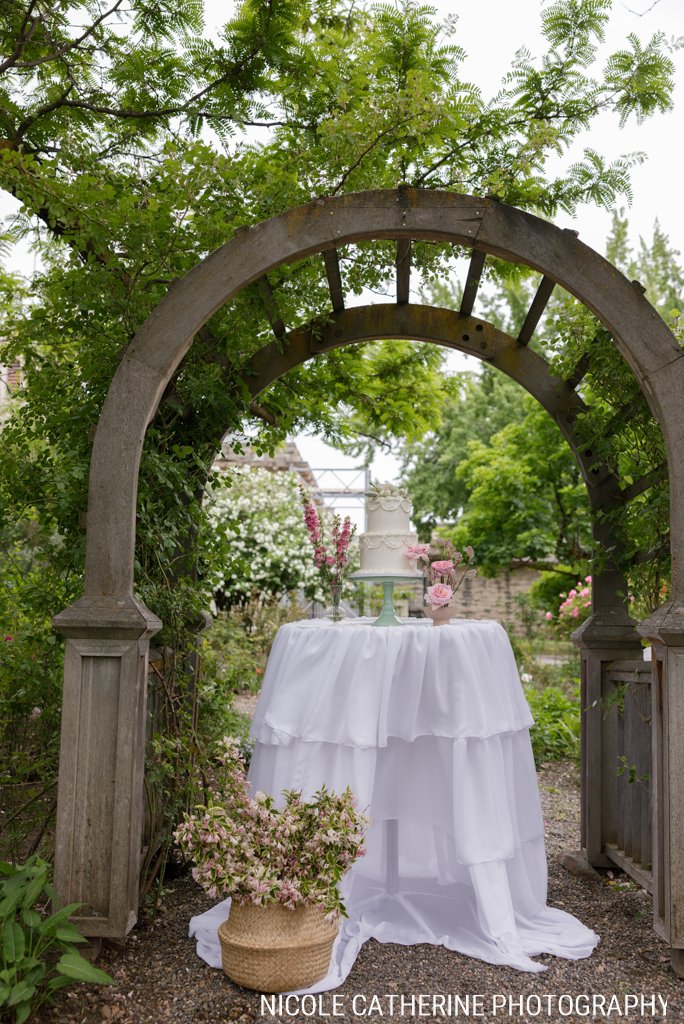 Wedding cake displayed under a garden arch