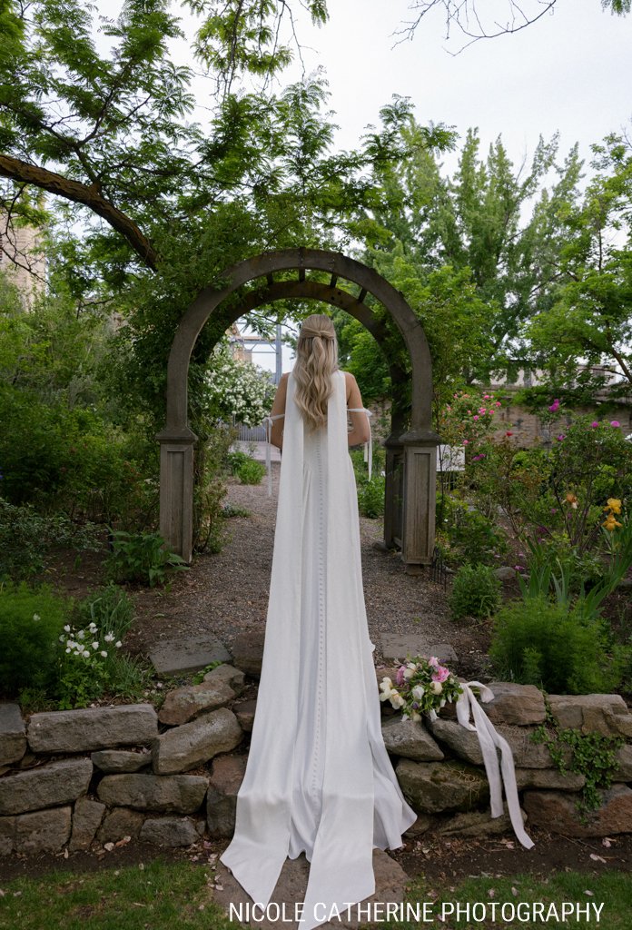 Bride walking through the garden arbor