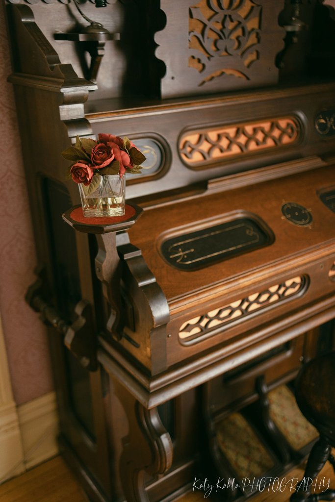 Antique parlor organ with a small vase of roses inside the house