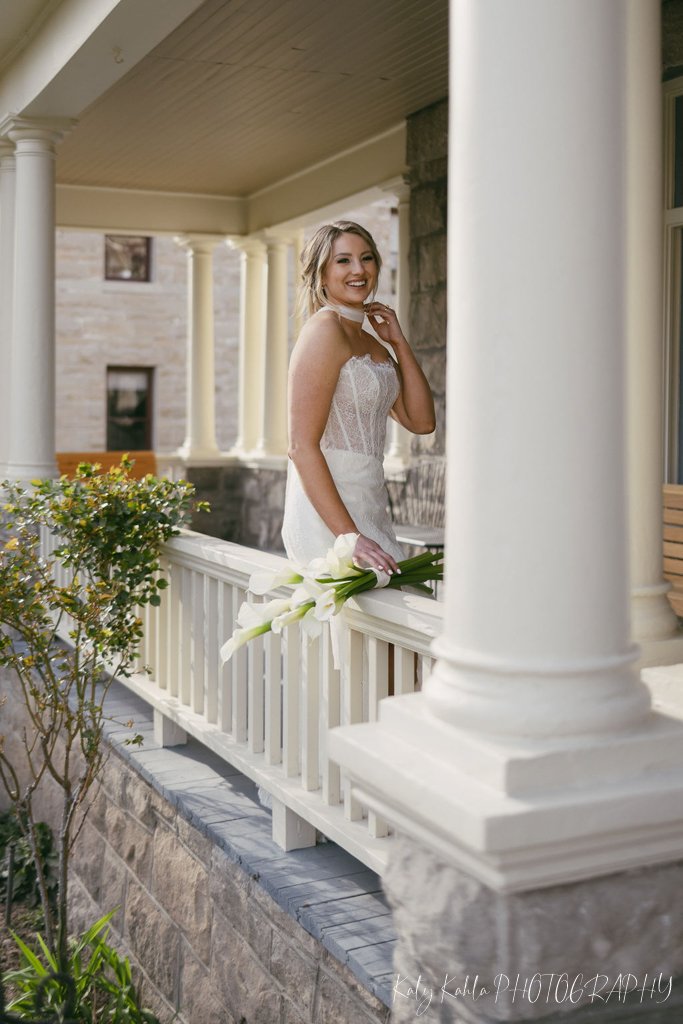 Bride smiling on the porch with her bouquet