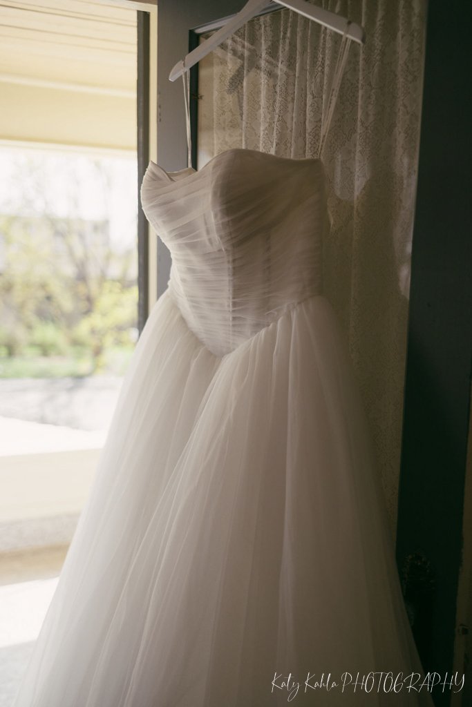 Wedding dress hanging in a sunlit window